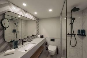 a bathroom with a shower and a toilet and a sink at DoubleTree by Hilton Berlin Ku'damm in Berlin