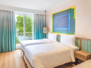 瓦加托ibis Styles Goa Vagator - An Accor Brand的一间有两张床和一扇大窗户的卧室