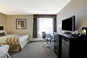 a hotel room with a bed and a desk with a television at Radisson Hotel & Conference Centre West Edmonton in Edmonton