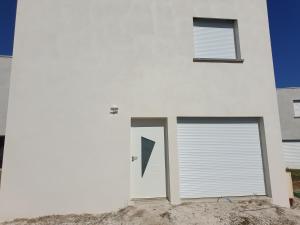 a white house with two garage doors on it at MAISON C in Saint-Jean-de-Thurigneux