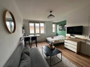 a living room with a couch and a desk at Appartement proche Paris et métro - Parking privé in Maisons-Alfort