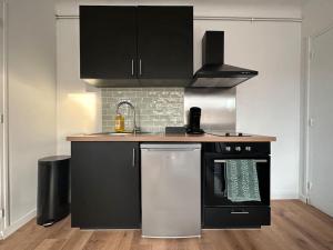 a kitchen with a black stove and a sink at Appartement proche Paris et métro - Parking privé in Maisons-Alfort