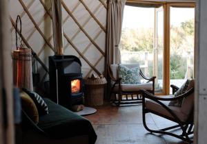 uma sala de estar com um fogão a lenha num quarto em Tree Field Yurt at Moor Farm em Godshill