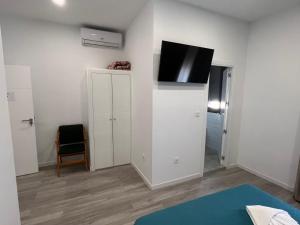 a bedroom with a tv on a white wall at Hostal Galaico in Madrid