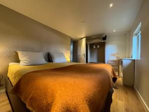 een slaapkamer met een groot bed en een oranje deken bij Plompeblad Guesthouse Giethoorn in Giethoorn