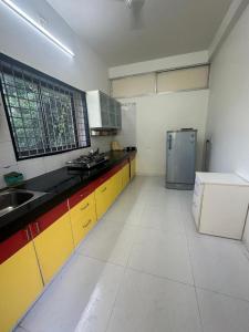 een keuken met gele en witte kasten en een koelkast bij Saikrishna Farm Near Adani Shantigram Ahmedabad in Adalaj