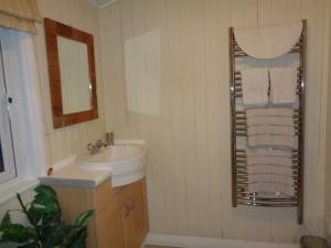 a bathroom with a sink and a mirror at Log Cabin, Conveniently Situated halfway between Stratford and Warwick in Stratford-upon-Avon