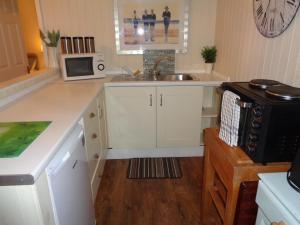 een keuken met een wastafel en een magnetron bij Log Cabin, Conveniently Situated halfway between Stratford and Warwick in Stratford-upon-Avon