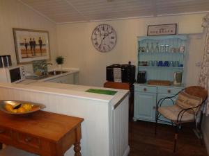 a kitchen with a counter and a clock on the wall at Log Cabin, Conveniently Situated halfway between Stratford and Warwick in Stratford-upon-Avon
