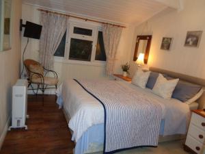 een slaapkamer met een bed en een stoel en 2 ramen bij Log Cabin, Conveniently Situated halfway between Stratford and Warwick in Stratford-upon-Avon
