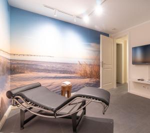 a room with a chair and a painting on the wall at Smuk Huus in Nieblum
