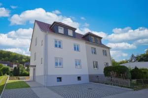 ein großes weißes Haus mit einem Dach in der Unterkunft Apartments Am Siebenborn in Eisenach