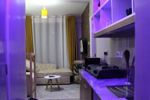 uma cozinha com iluminação roxa e uma sala de estar em Artsy Urban 1Br along Kiambu Road with a pool and scenic views em Kiambu