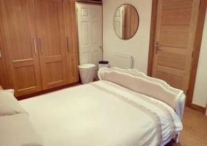 1 dormitorio con 1 cama blanca grande y espejo en Self contained 1 bedroomed Annex with street parking, en Ilkeston