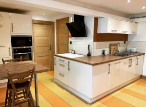 a kitchen with white cabinets and a wooden table at Annie the Annex, A self contained home from home fully equipped space with street parking in Ilkeston