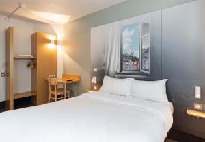 聖博內德穆雷的住宿－B&B HOTEL Lyon Saint-Bonnet Mi-Plaine，酒店客房设有一张大床和一张书桌。