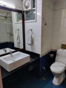 bagno con lavandino, servizi igienici e specchio di Darjeeling La Resort a Darjeeling