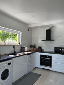 a white kitchen with a sink and a dishwasher at Casa do Cedro no Campo in Correias