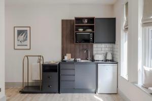 a kitchen with a sink and a microwave at Tooting - Your Apartment in London