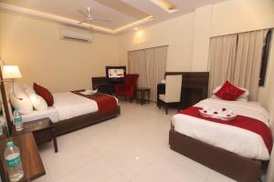 een hotelkamer met 2 bedden en een bureau bij Hotel Indira Nikunj in Rishīkesh