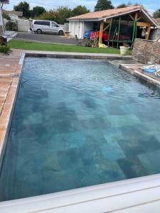 una gran piscina de agua azul en un patio en Villa Familiale bassin d'Arcachon, en Biganos