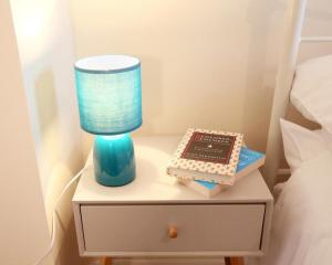 a nightstand with a blue lamp and a book at Central Norwich House W Parking Ginger&gold in Norwich