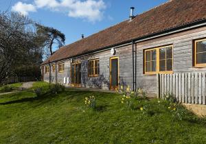 una casa con un patio de hierba delante de ella en The Grainstore at Moor Farm, en Godshill