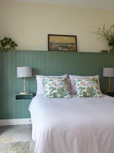 1 cama en un dormitorio con una pared verde en The Grainstore at Moor Farm, en Godshill