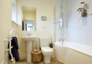a bathroom with a toilet and a sink and a tub at The Grainstore at Moor Farm in Godshill