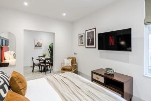 a white bedroom with a bed and a table at Tooting - Your Apartment in London