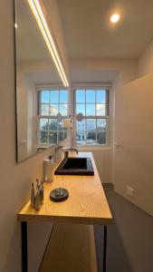 uma cozinha com um balcão com um lavatório e duas janelas em Matriz 55, Hostel & Suites em Ponta Delgada
