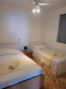 Apartments with a parking space Sutivan, Brac - 5629 في سوتيفان: سريرين في غرفة بجدران بيضاء