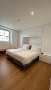 um quarto com uma cama grande e lençóis brancos em Matriz 55, Hostel & Suites em Ponta Delgada
