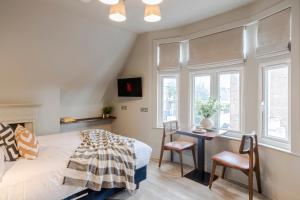 a bedroom with a bed and a desk and windows at Tooting - Your Apartment in London
