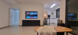 a living room with a table and a tv on the wall at Amazing apartment in Bat Yam