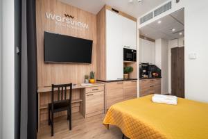 een slaapkamer met een geel bed en een televisie aan de muur bij Warsview Apartments in Warschau