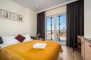een slaapkamer met een bed met een gele sprei bij Warsview Apartments in Warschau