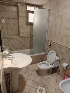 a bathroom with a white toilet and a sink at منامي للشقق المخدومة-كورنيش الخبر-اقتصادي in Al Khobar