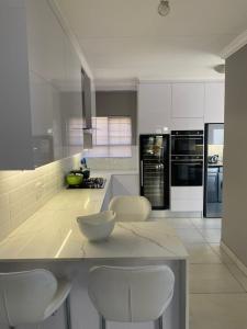 uma cozinha com armários brancos e um balcão com cadeiras brancas em Modern Serene 3 Bedroom Villa em Joanesburgo