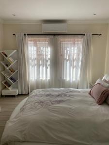 um quarto com uma cama e uma janela com cortinas brancas em Modern Serene 3 Bedroom Villa em Joanesburgo