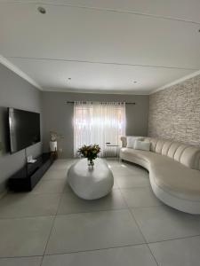 uma sala de estar com um sofá grande e uma televisão em Modern Serene 3 Bedroom Villa em Joanesburgo