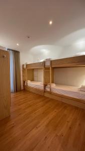 um quarto com 2 beliches e piso em madeira em Matriz 55, Hostel & Suites em Ponta Delgada