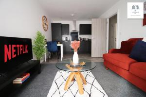 a living room with a red couch and a glass table at New Modern 1 Bedroom Apartments - Prime Location - By EKLIVING LUXE Short Lets & Serviced Accommodation - Cardiff in Cardiff