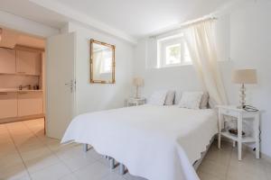 Dormitorio blanco con cama blanca y espejo en Residence Mont-Blanc Apartment, en Ginebra