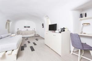 a white living room with a couch and a tv at Ambition Suites in Oia
