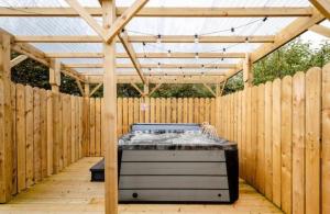 a wooden pergola with a bed in a backyard at Boa Island Retreat in Aghnablaney