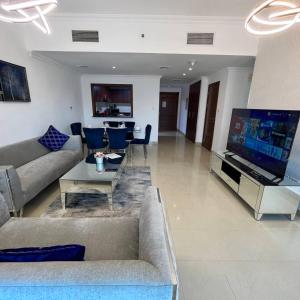 uma sala de estar com sofás e uma grande televisão em Pure Living - Spacious & Relaxing 2BR Apartment in Dubai Marina em Dubai