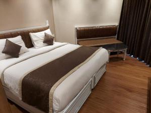 a bedroom with a large bed and a bench at Hotel Shreehari - Puri in Puri