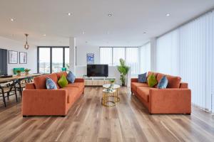 Sala de estar con 2 sofás naranjas y TV en Host & Stay - The Knight Street Penthouses, en Liverpool