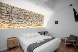 a bedroom with a stone wall above a bed at 32 De Agosto ROOMS in San Sebastián
